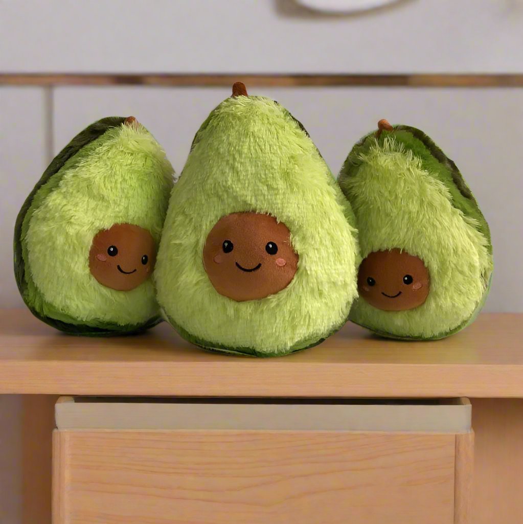 Three Avo Pals plushies with cute faces, arranged together on a wooden table in a cozy room, Avo Pals, Avocado plushie, Family, Cute avocado toy, Small Medium Large sizes, Cozy decor, Plushies, Plush Dolls, Cute Plush, Plush, Soft Dolls, Toy Dolls, Toy, Toys, Squishy, Soft, Soft Toys, Stuffed Toys, Plush Toy, Plush Toys, Premium, Quality, Adorable, Cuddly, Playful, Collectibles, Huggable, Kids Toys, Children's Gifts, Gift Ideas, Gift, Gifts, Plush, Teddy Bear.