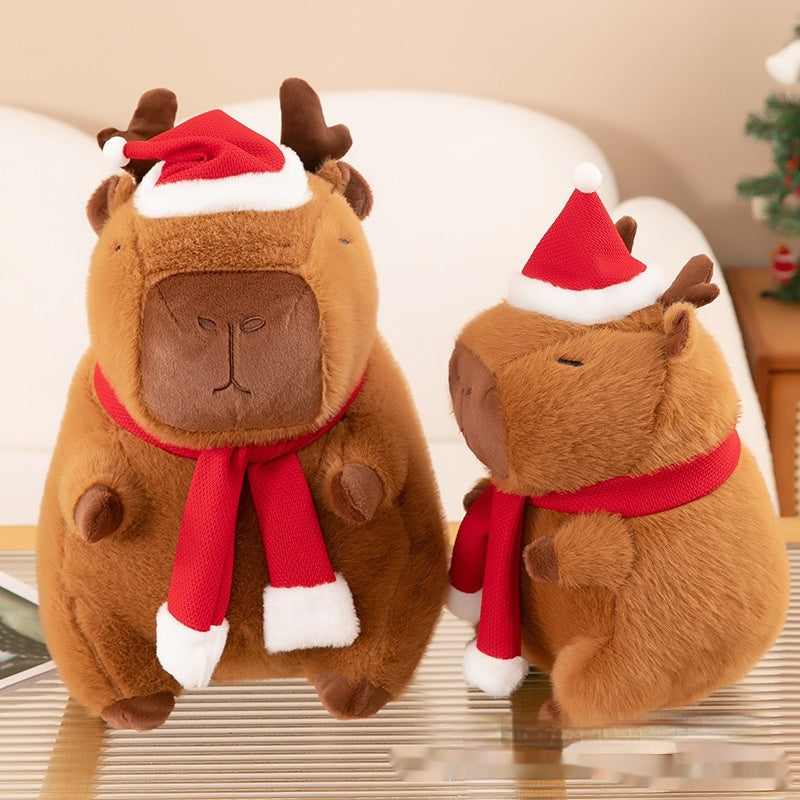 Two festive capybaras sitting on a table. Christmas Plushie, Capybara Plushie, Squishmallow.