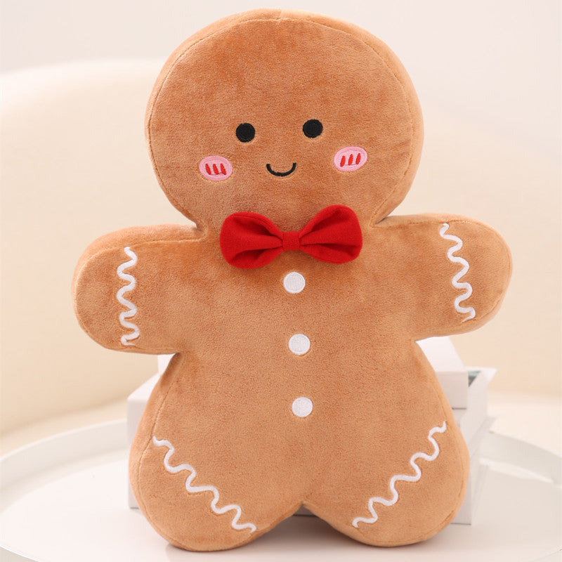 A gingerbread pal plushie on a white table. Christmas Plushie, Gingerbread Plushie, Squishmallow.